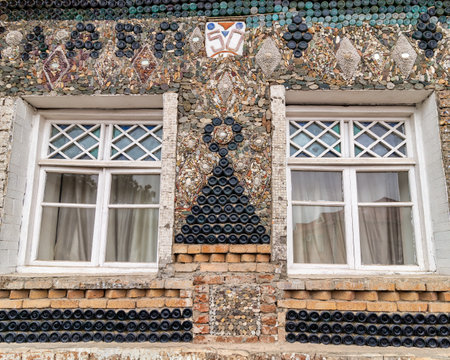Glass bottle decoration on the Bottle House in Ganja, Azerbaijan - a triangular shape with top circle made from stacked bottles, mediating two wooden windowsの写真素材