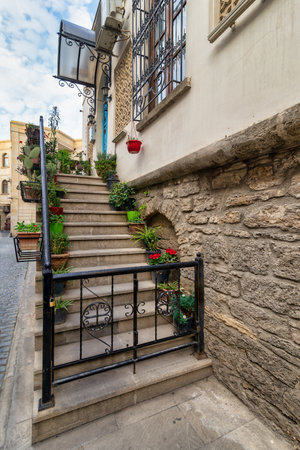 Staircase in Icherisheher, Baku, Azerbaijan features vibrant pots of flowers and greenery on each step. The cobblestone street and stone wall create a picturesque urban settingの写真素材