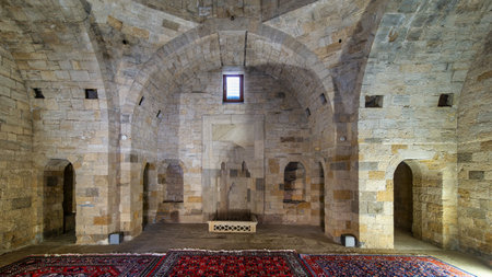 Inside Shirvanshahs Palace Mausoleum, explore intricate stone archways and arranged rugs that...