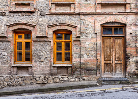 A well-preserved building features unique stonework, wooden arched door, and ornate windows,...