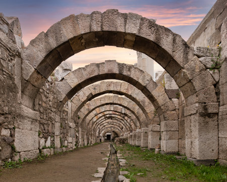 The remnants of the Agora of Smyrna, marveling at the impressive stone arches as the sun sets, casting a warm glow over the archaeological site in Izmir, Turkey.の写真素材