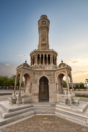 The historic Izmir Clock Tower in Turkey, intricately designed with ornate details, proudly displays its beauty in Konak Square as evening approaches, casting a warm glow over the areaの写真素材