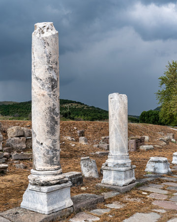 Ancient weathered marble columns stand among ruins at the Asklepion Ruins in Bergama, Turkey, archaeological site under a dramatic stormy sky. Historical landscapeの写真素材
