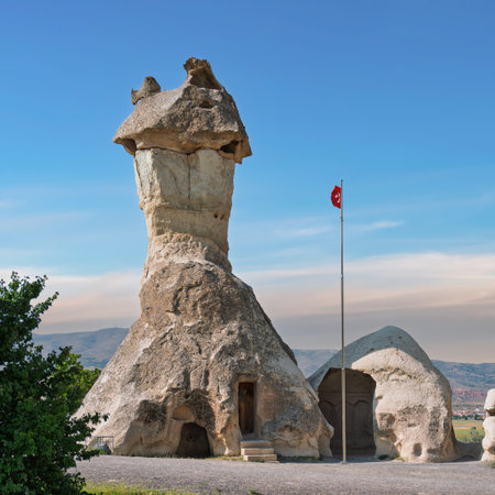 A fairy chimney rock formation, an ancient cave dwelling, with the Turkish flag at Pasabag Valley, Cappadocia, Nevsehir, Turkeyの写真素材