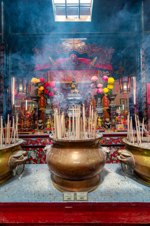Kuala Lumpur, Malaysia - Feb. 16, 2025: Sin Sze Si Ya Temple. Ornate temple interior with burning joss sticks, rising smoke, and vibrant traditional Chinese decorations at the altarの写真素材