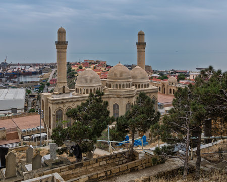 Overlooking the Caspian Sea, the historic Bibi-Heybat Mosque in Baku, Azerbaijan, features intricate domes and minarets. A cemetery and pine trees are in the foregroundの写真素材