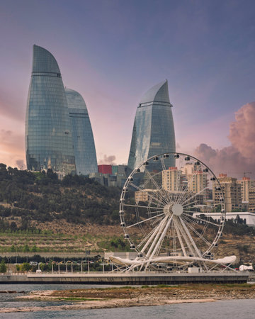 Flame Towers and Baku Eye Ferris Wheel in Baku, Azerbaijan, with a dramatic cloudy sky. Modern architecture and city view from the Caspian Sea.の写真素材