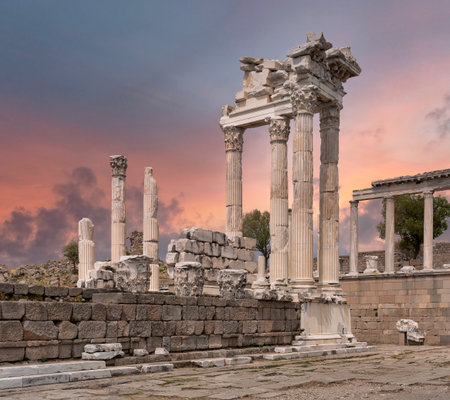 Ancient Temple of Trajan ruins at Pergamon, Bergama, Turkey. Majestic Roman columns and stone blocks under a dramatic, colorful sunset sky. Historical archaeological site.の写真素材