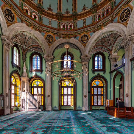 Ornate sunlit interior of Salepcioglu Mosque, Izmir, Turkey. Features a grand dome, Islamic calligraphy, large chandelier, vibrant stained glass windows, and a patterned turquoise carpetの写真素材