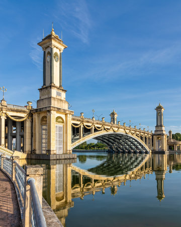 Grand Seri Gemilang Bridge with ornate towers and clock faces, reflected in calm water under a blue sky in Putrajaya, Malaysiaの写真素材