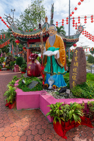 Statue of Yue Lao at Thean Hou Temple, Kuala Lumpur, Malaysia. Colorful deity with book, staff, red bag, and stone tablet, surrounded by festive red lanterns.の写真素材