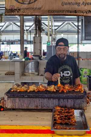 Bandar Seri Begawan, Brunei - Feb. 26, 2025: Man grilling chicken and skewers at Amings BBQ stall, Gadong Night Market. Authentic street food sceneのeditorial素材