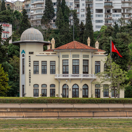 Izmir State Theatre, DT Konak Sahnesi, a historic building with a Turkish flag, surrounded by trees and modern apartments in Izmir, Turkeyの写真素材
