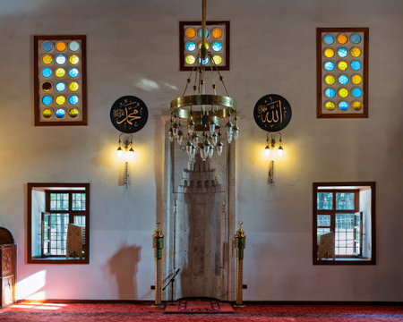 Interior of Shems-i Tebrizi Mosque and Tomb, Konya, Turkey. Features mihrab, ornate chandelier, colorful stained glass windows, and Islamic calligraphy. A sacred worship space.の写真素材