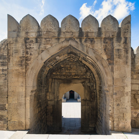 Ancient stone archway and crenellated wall in the Courtyard of the Palace of the Shirvanshahs,...