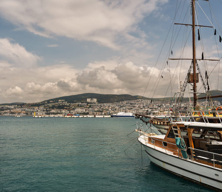 Kusadasi, Turkey. Harbor scene with a traditional gulet boat, city buildings on the hillside, and a...