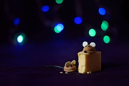 Figures of mice made by hand from a walnut shell and a piece of cheese on a black background. Happy...