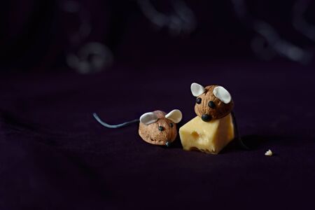 Figures of mice made by hand from a walnut shell and a piece of cheese on a blackの写真素材