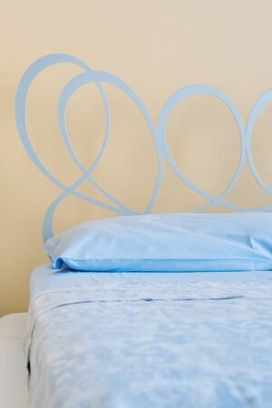 Large comfortable bed with wrought-iron headboard in a stylish room interior. close- upの写真素材