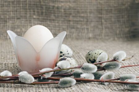 Composition of Easter eggs on a background of rough canvas. An egg in a stand in the form of a...
