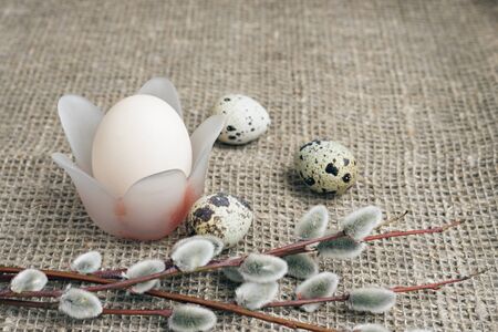 Composition of Easter eggs on a background of rough canvas. An egg in a stand in the form of a...