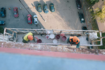 Industrial climbers while painting the outer wall of the facade of a tall apartment building.Top...