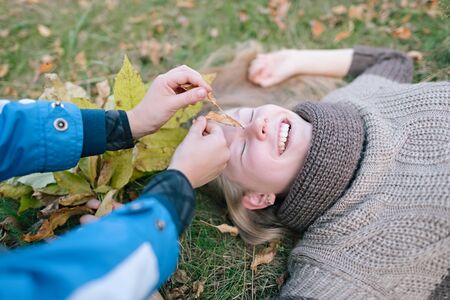 Children indulge lying on the grass in the autumn park. Emotions Close-upの写真素材