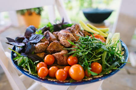 Shish kebab surrounded by greens and vegetables, served on a beautiful large platter. Traditional central Asian cuisine. The National dishの写真素材