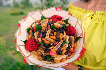 A bouquet of dried fruits and candied fruits in the hands of the girl. An original birthday present. Close-upの写真素材