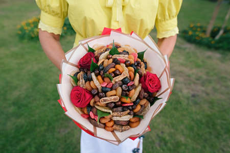 A bouquet of dried fruits and candied fruits in the hands of the girl. An original birthday present. Edible bouquet の写真素材