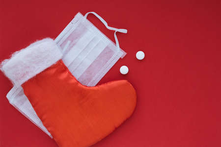New Years boot for gifts and a medical surgical mask with pills on a red background. Copy space for...