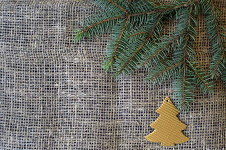 Green natural spruce branch and golden spruce made of paper on a gray mat. Burlap with copy space. Christmas and new year conceptの写真素材