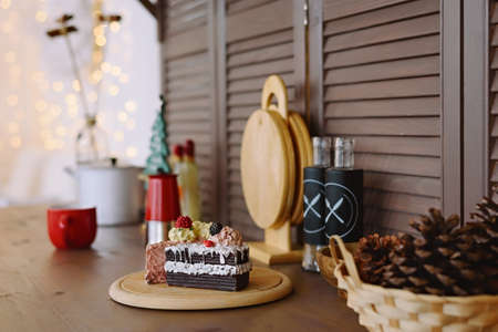 Pieces of cake and utensils in a kitchen with a rustic wooden wall with a christmas garland in the backgroundの写真素材
