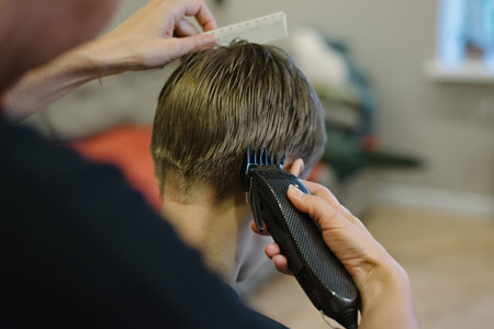 Woman cuts hair of boy at home. Homemade haircutの写真素材