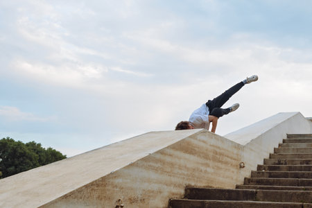 Young caucasian man jumping on concrete bridge. parkour pose in city environment and sky