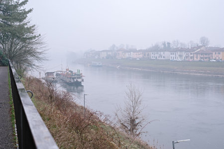 View of the river and city surrounded by fog in winter. Pleasure boat on the river. Pavia. Italy. Lombardyの写真素材