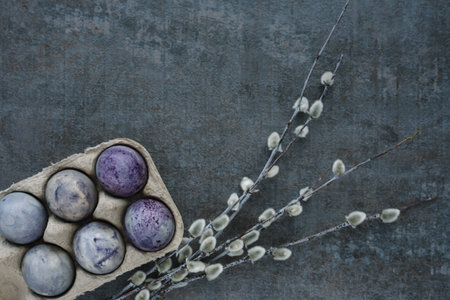 Happy Easter concept. Cosmic-colored decorated easter eggs willow feather on trendy dark textured...