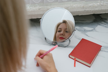 Reflection in mirror of girl who writes letter. Home Conceptの写真素材