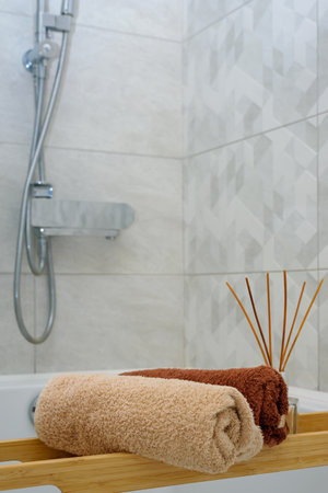 Clean towels and aroma diffuser on wooden tray in contemporary bathroom. Concept wellness and healthy. Closeupの写真素材