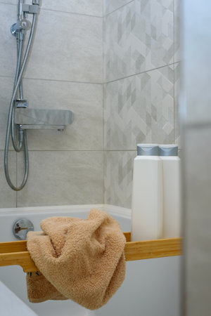 Wrinkled towel and shampoo bottles or shower gel on wooden tray after taking shower in bathroom...