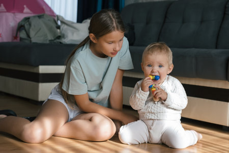 Baby playing on floor with educational toys with sister teen. Children at home
