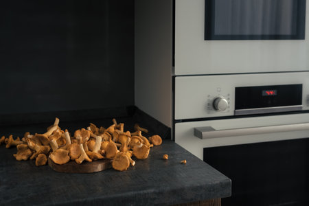 Kitchen dark counterand and raw chanterelle mushrooms prepared for cookingの写真素材