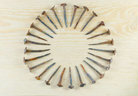 Old hand-forged nails laid out in the form of a sun symbol on a pine board.の写真素材