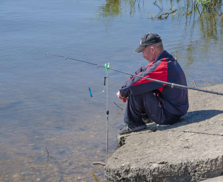 Zelenodolsk, Tatarstan, Russia - June 10, 2015: The Volga River. A fisherman sits on the shore and sadly looks at the water.のeditorial素材