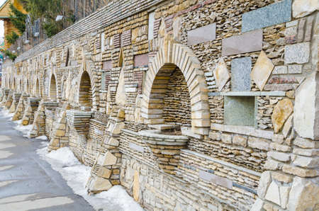 Stone fence. The stone wall is made partially from natural stone, partly of artificial material - brick and tile.の写真素材