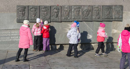 Kazan, Republic of Tatarstan, Russia - February 20, 2016: Part of the monumental complex of Musa Jalil and his associates. The bas-relief in memory of "group Kurmashev". School excursion in Kazan. Schoolgirls look at portraits of heroes.のeditorial素材