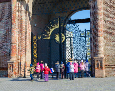 Kazan, Republic of Tatarstan, Russia - February 20, 2016: Historic and Architectural Complex of the Kazan Kremlin. UNESCO World Heritage Site. School excursion. The teacher-guide and group of schoolchildren near iron gate of the tower Syuyumbike.のeditorial素材