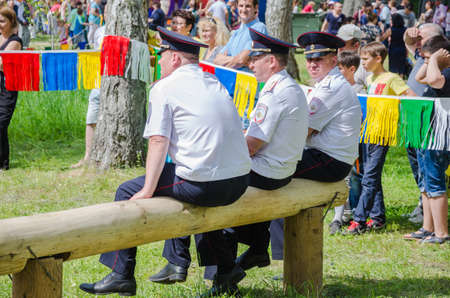 Kazan, Republic of Tatarstan, Russia - May 28, 2016: Police officers have a rest sitting on a log and watch the competitions. Sabantuy (translated from Tatar - feast of the plow) is a traditional celebration of the end of spring field work.のeditorial素材