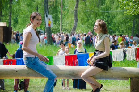 Kazan, Republic of Tatarstan, Russia - May 28, 2016: Girls sit on a log and prepare for fight on bags. Sabantuy (translated from Tatar - feast of the plow) is a traditional celebration of the end of spring field work.のeditorial素材