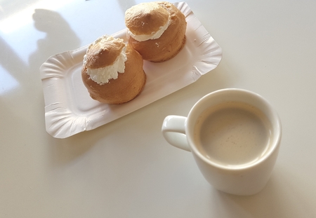 Two fresh and delicious cream buns and an espresso on an office table to celebrate the start of a...